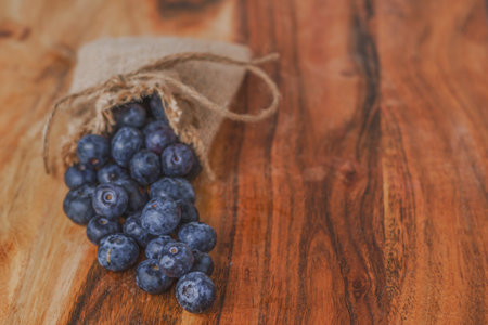 fresh blueberries in a raffia bag on a wooden tableの写真素材