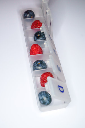 blueberries and raspberries in a pill box drug-free health concept