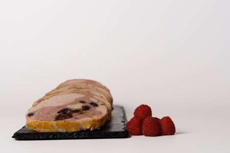 close-up of a chicken stuffed with raspberry and goat cheese with a bowl of raspberry sauce isolated...