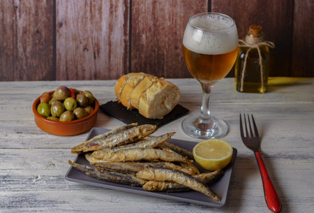 battered fried anchovies. fried anchovies in batter typical of southern spain with olives, bread and beerの写真素材
