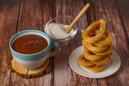 hot chocolate with churros in a white and blue cup, typical spanish breakfast on a wooden tableの写真素材