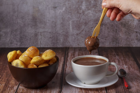 woman spreading a sugared donut with a wooden fork on a hot chocolate in a white mugの写真素材