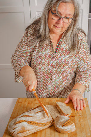 white-haired woman cutting slices of freshly baked homemade bread