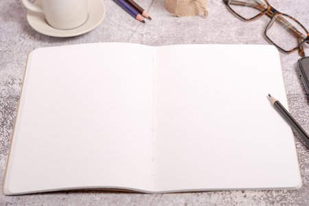 top view of a notebook with blank pages, glasses, coffee mug and pencilsの写真素材