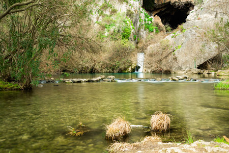 mountain river crystal clear water with waterfall and cave in the backgroundの写真素材