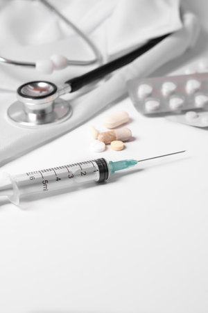 stethoscope, pills and syringe on a doctor's gown on a white background and copy spaceの写真素材