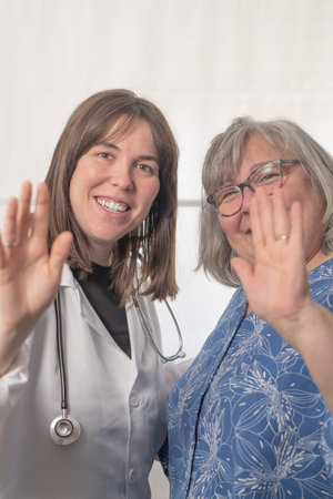 woman doctor and patient greeting the camera happy and smiling in the doctor's officeの写真素材