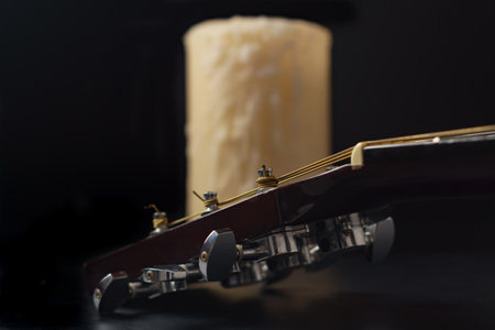 Spanish guitar neck with a candle in the background on a black backgroundの写真素材