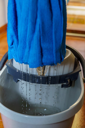 closeup of a blue mop dripping drops of water into its bucket