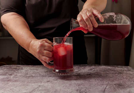 waitress dressed in black serving a pitcher of sparkling summer red wine on ice from a glass decanterの写真素材