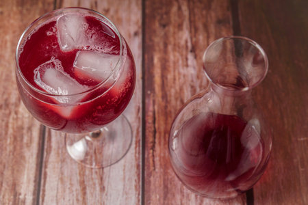 top view of a sparkling glass of summer red wine on the rocks next to a decanter on a wooden tableの写真素材