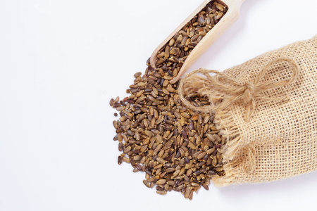 raffia cloth bag with a wooden spoon with milk thistle seeds or Silybum marianum healing medicinal plant for liver isolated on white backgroundの写真素材