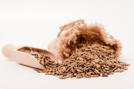 raffia cloth bag with a wooden spoon with milk thistle seeds or Silybum marianum healing medicinal plant for liver isolated on white backgroundの写真素材