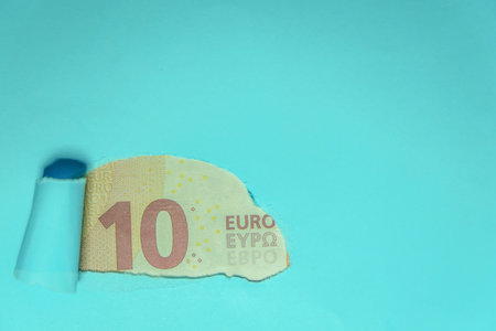 part of a ten-euro bill seen through a torn green cardboardの写真素材