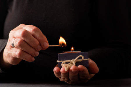 hands of a woman lighting a candle with a match with a black background and copy spaceの写真素材