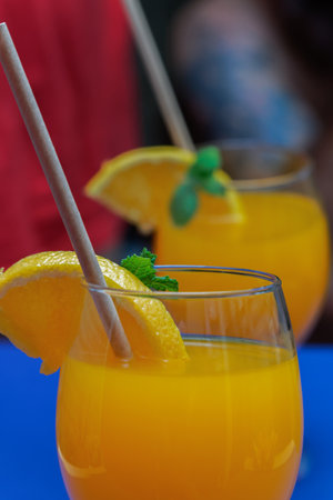 close-up of an orange juice with orange slice, straw and mint reflected in a mirrorの写真素材