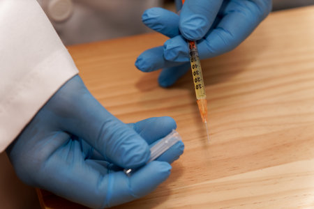 doctor's hands in blue latex gloves with a syringe in his hand on the table in his office