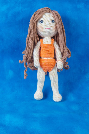 close-up of a handmade amigurumi doll on a blue backgroundの写真素材