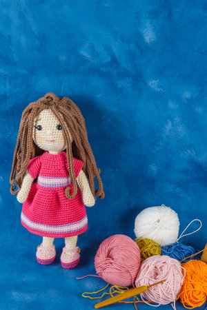 amigurumi doll handmade on a blue background with the yarns used for its elaborationの写真素材