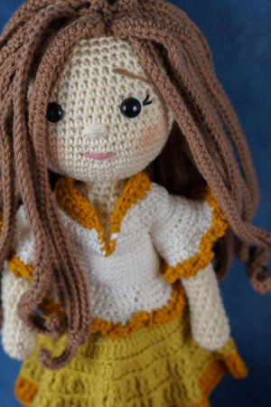 close-up of a handmade amigurumi doll on a blue backgroundの写真素材