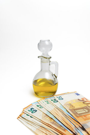 euro banknotes in front of a bottle of olive oil isolated on a white background, oil price rise conceptの写真素材