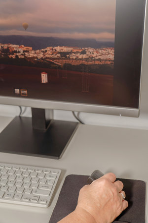 woman's hand working at her computer with an ergonomic vertical computer mouse to avoid hand painsの写真素材