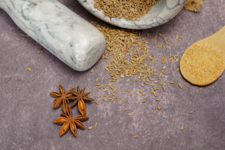 Whole dried anise seeds (Pimpinella anisum) in a ceramic mortar and pestle, with ground anise and star aniseの写真素材