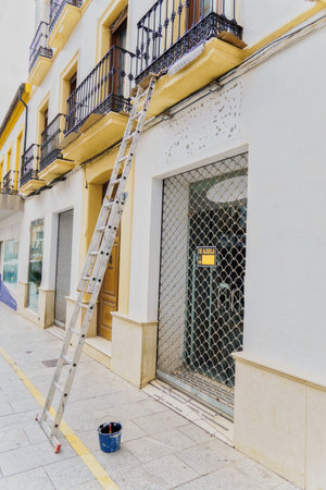 business under construction with a ladder on the facade and a paint bucket on the floor; for rent