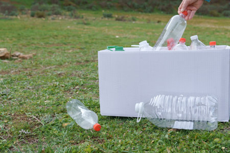 woman collecting empty plastic bottles in the field to recycle, concept of ecology and respect for the environment.の写真素材