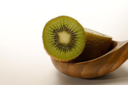 close-up of a fresh kiwi cut in half in a wooden spoon isolated on a white background and copy spaceの写真素材