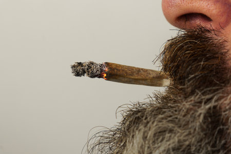 close-up of a bearded man smoking a medical marijuana jointの写真素材
