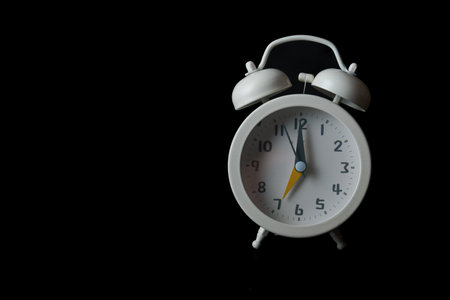 close-up of a white alarm clock isolated on a black backgroundの写真素材