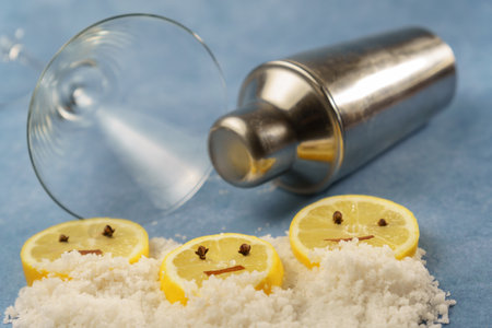 lemon slices with cloves and cinnamon forming a smiley face on a pile of salt next to a cocktail...