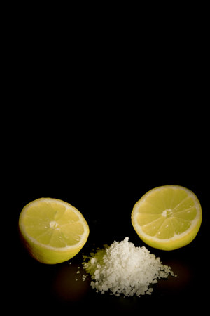 lemon cut in half with a pile of salt isolated on black background and copy spaceの写真素材