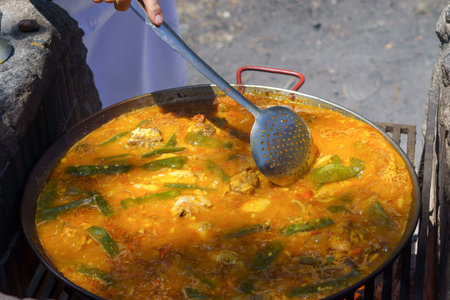 close-up of the hand of a cook cooking a typical Spanish paella over a fire in the countrysideの写真素材