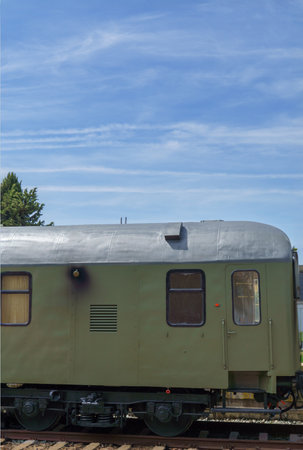 old train carriage stopped at the station in the background a blue sky with cloudsの写真素材