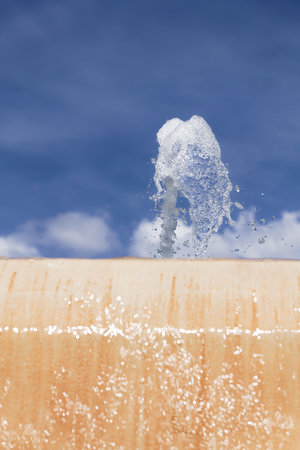 stream of water coming out of a public fountain with a blue sky in the backgroundの写真素材
