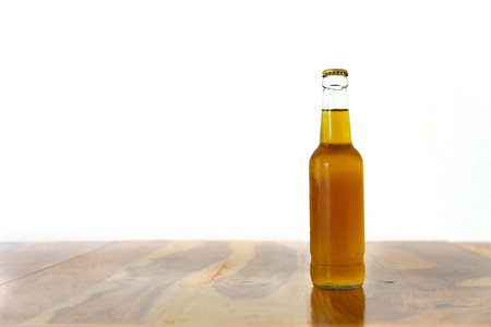 bottle of cold beer with frost drops on a wooden table with a white wall in the backgroundの写真素材