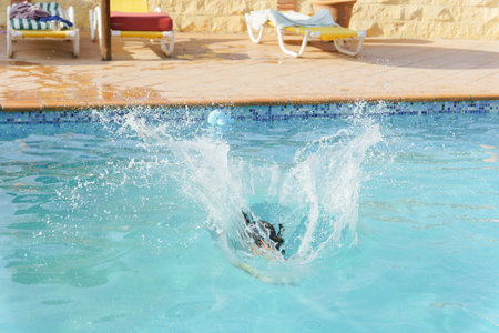 unrecognizable person jumping into a splashing pool