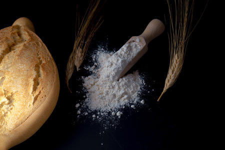 bread with flour, ears of wheat and a rolling pin isolated on a black background and copy space