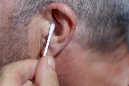 close-up of a man cleaning his ears with a cotton swab