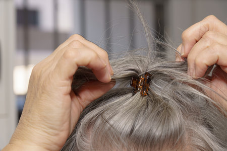white-haired woman making a ponytail with a hair clipの写真素材