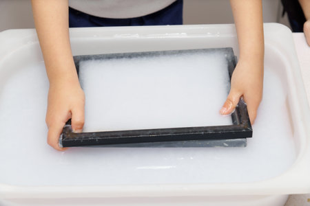 close-up of a child's hands making eco-friendly recycled paper at home