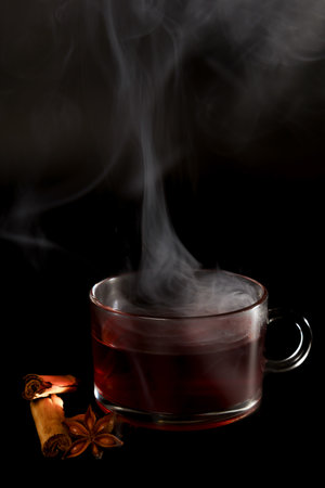 steaming cup of hot tea with star anise and cinnamon stick isolated on black background and copy spaceの写真素材