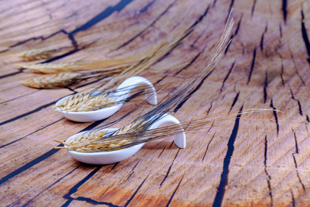 white ceramic spoons with ears of wheat on a wooden background