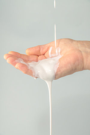 close-up of woman's hand pouring white creamの写真素材