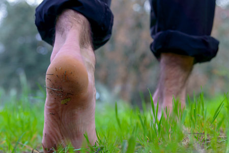Close-up of dirty, bare feet walking on green grass, embracing natureの写真素材