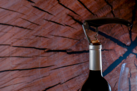 Wine bottle with corkscrew on rustic wood background, ready to be enjoyed