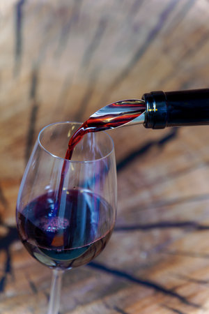 Red wine being poured into a glass with a wooden background