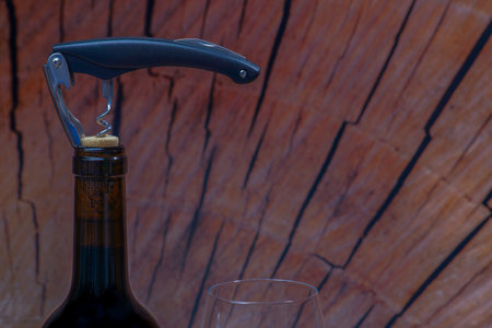 Wine bottle with corkscrew and wineglass on wooden backgroundの写真素材